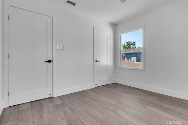 unfurnished bedroom featuring baseboards, visible vents, and light wood-style flooring