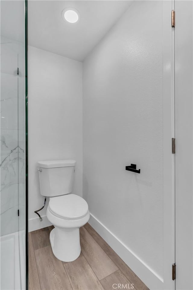 bathroom with toilet, walk in shower, wood finished floors, and baseboards