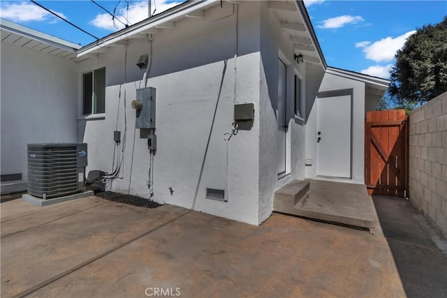 exterior space with cooling unit, a patio area, fence, and a gate