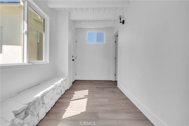 hall featuring beamed ceiling, wood finished floors, and baseboards