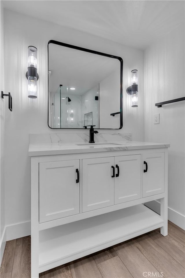 bathroom featuring a shower stall, baseboards, vanity, and wood finished floors