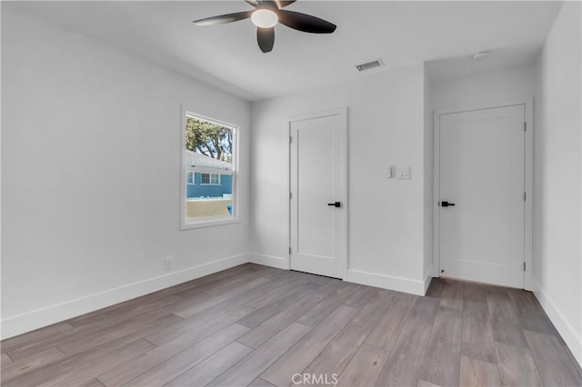 unfurnished bedroom featuring light wood-style floors, visible vents, a ceiling fan, and baseboards