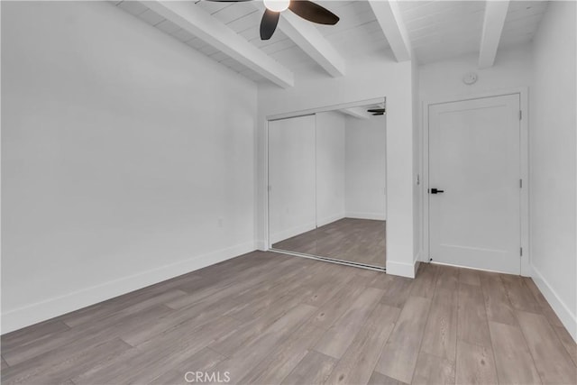 unfurnished bedroom featuring a closet, light wood-type flooring, beam ceiling, and ceiling fan