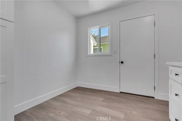empty room featuring baseboards and light wood-type flooring