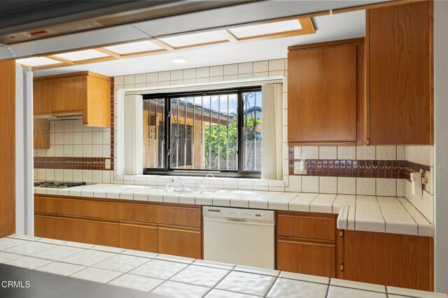 kitchen featuring dishwasher, brown cabinetry, tasteful backsplash, and cooktop
