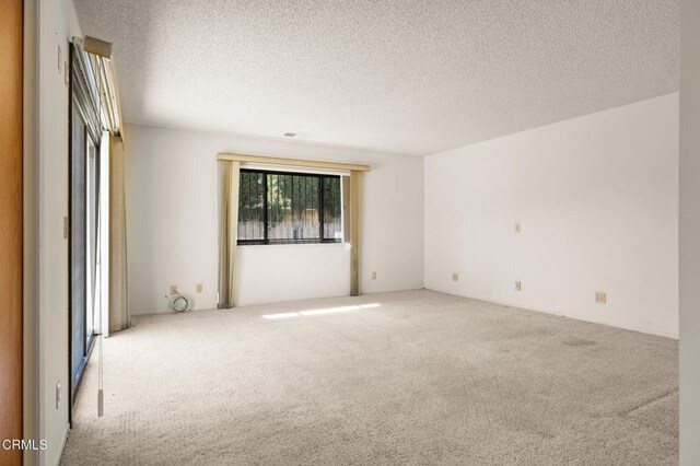 carpeted empty room featuring a textured ceiling