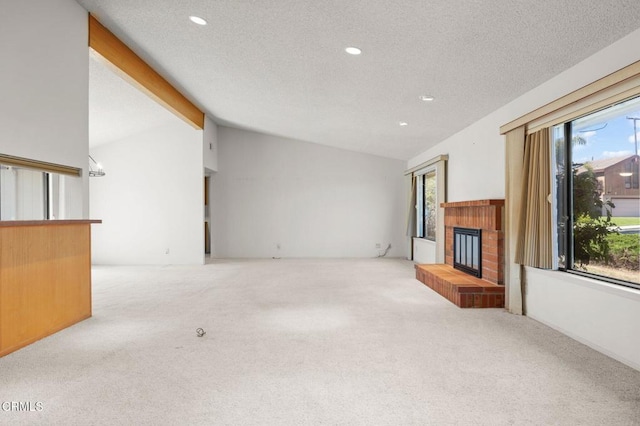 unfurnished living room featuring a fireplace, vaulted ceiling, a wealth of natural light, and carpet