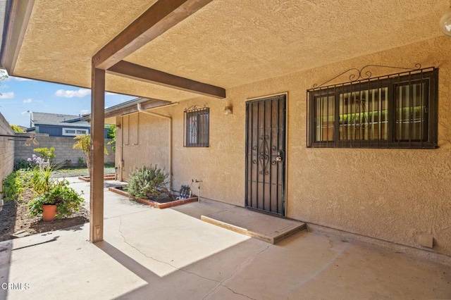 entrance to property with a patio area, stucco siding, and fence