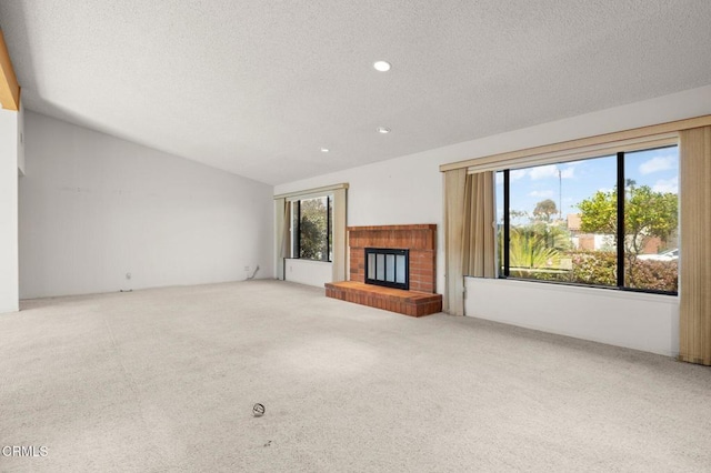 unfurnished living room with a textured ceiling, carpet floors, a fireplace, lofted ceiling, and recessed lighting