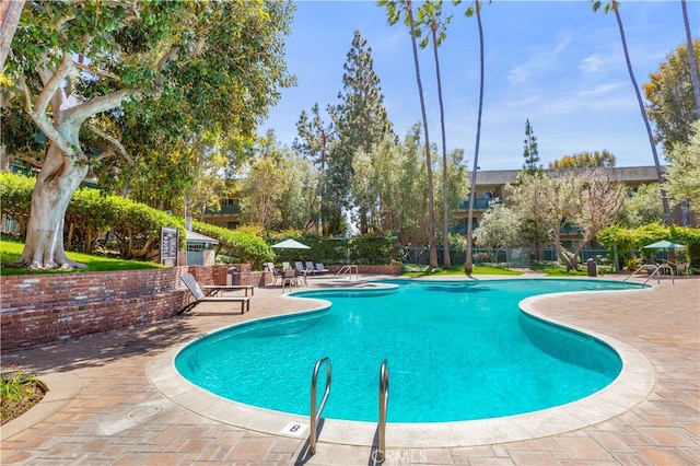 community pool with a patio area and fence