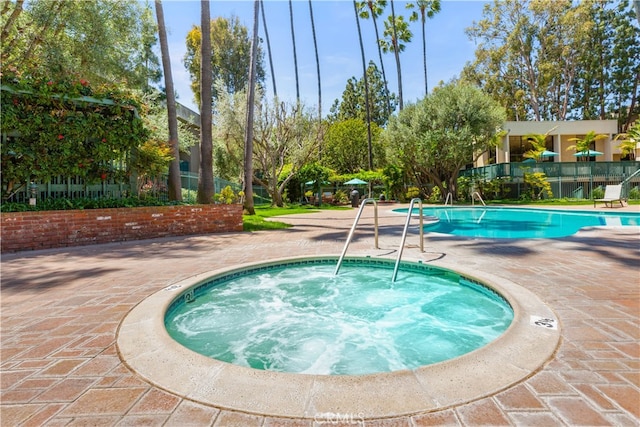 pool featuring fence, a hot tub, and a patio area