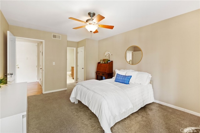 bedroom featuring visible vents, carpet floors, ensuite bath, baseboards, and ceiling fan