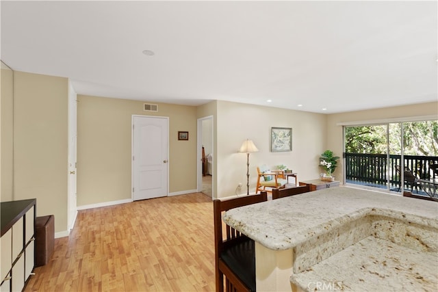 kitchen with light wood finished floors, baseboards, visible vents, recessed lighting, and light stone countertops