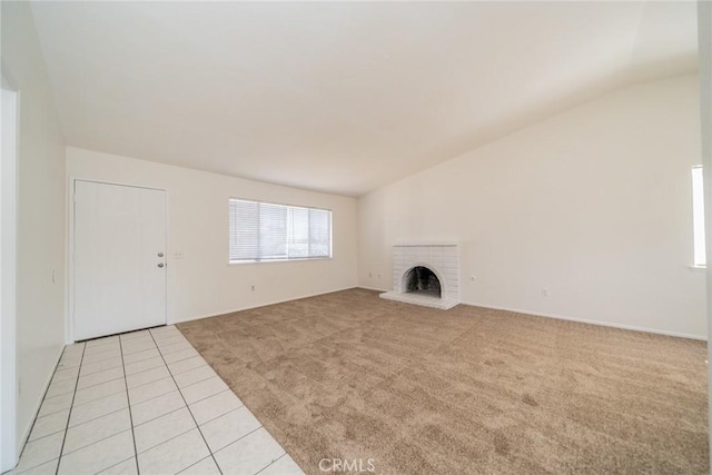 23607 Dracaea Ave, Moreno Valley, CA 92553 - unfurnished living room featuring light colored carpet, vaulted ceiling, a brick fireplace, light tile patterned floors, and baseboards