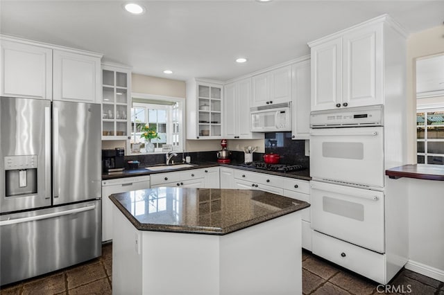 kitchen with white cabinets, glass insert cabinets, a sink, recessed lighting, and white appliances