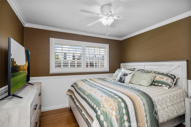 bedroom featuring ornamental molding, a wainscoted wall, a ceiling fan, and wood finished floors