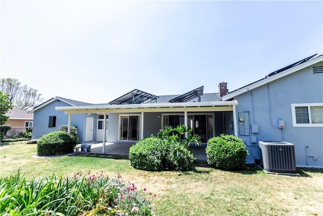 rear view of house with stucco siding, a yard, cooling unit, and a patio area