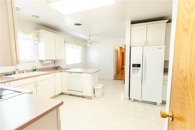 kitchen featuring light floors, white appliances, a sink, white cabinetry, and a peninsula