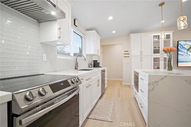kitchen featuring range hood, a sink, light wood-type flooring, appliances with stainless steel finishes, and white cabinetry