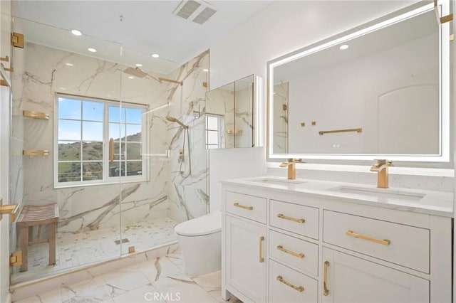 bathroom with marble finish floor, toilet, a sink, and a marble finish shower
