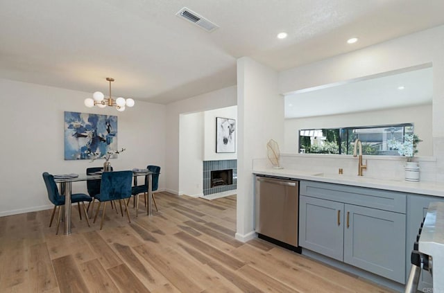 kitchen with a sink, dishwasher, backsplash, gray cabinetry, and visible vents