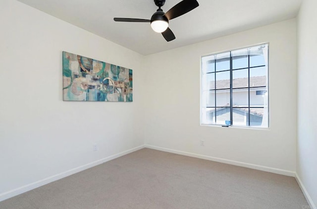 spare room with light carpet, a ceiling fan, and baseboards