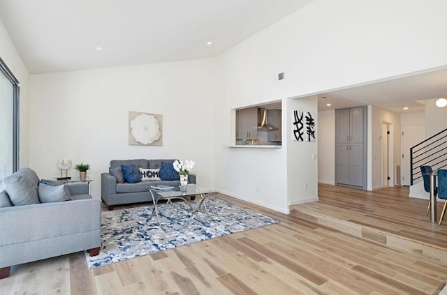 living room with vaulted ceiling, stairs, light wood-type flooring, baseboards, and recessed lighting