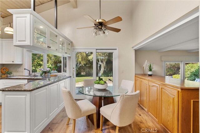 dining space featuring high vaulted ceiling, ceiling fan, beam ceiling, and light wood-type flooring