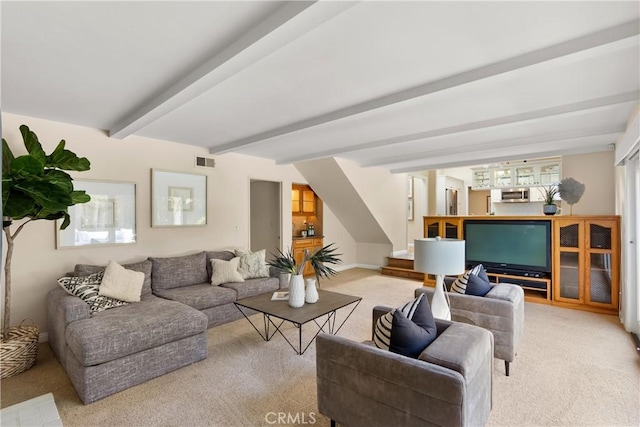 living room with visible vents, beam ceiling, and light carpet