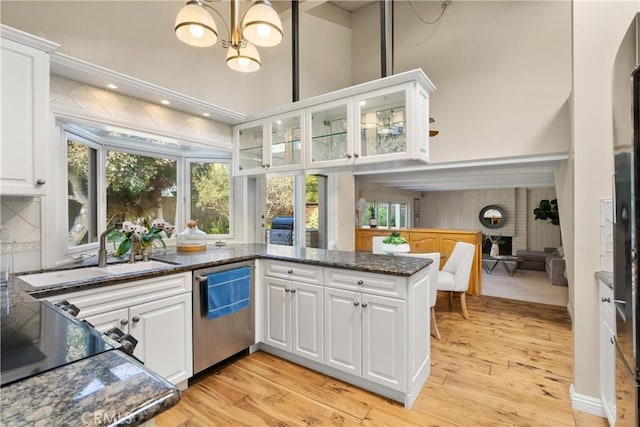 kitchen featuring white cabinets, an inviting chandelier, a sink, and light wood finished floors