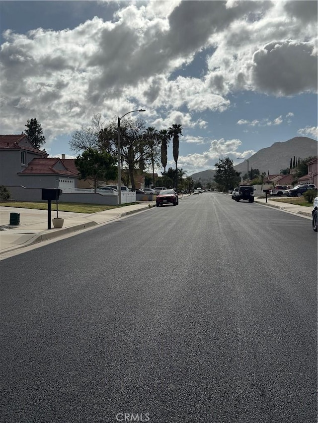 view of road with street lights, curbs, sidewalks, and a mountain view