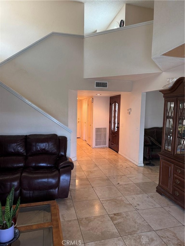living area featuring baseboards, visible vents, a high ceiling, and light tile patterned flooring