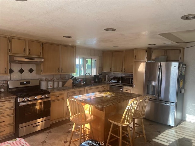 23680 Rhea Dr, Moreno Valley, CA 92557 - kitchen with a sink, a breakfast bar, under cabinet range hood, appliances with stainless steel finishes, and tasteful backsplash