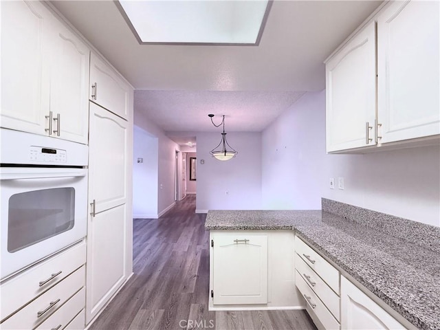 851 Ronda Mendoza Unit B, Laguna Woods, CA 92637 - kitchen with white oven, a peninsula, and white cabinetry
