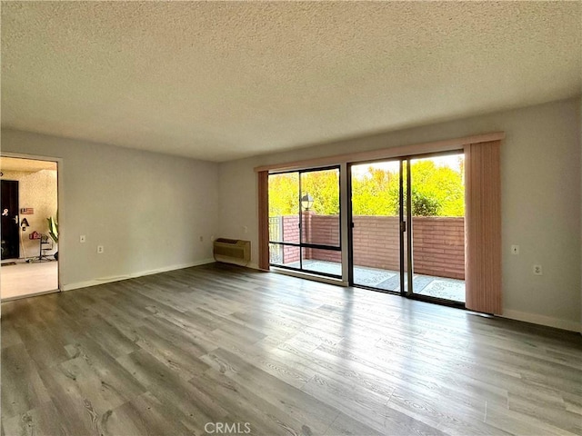 851 Ronda Mendoza Unit B, Laguna Woods, CA 92637 - spare room featuring wood finished floors, a textured ceiling, and a wall unit AC