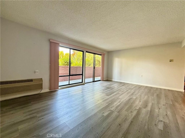 851 Ronda Mendoza Unit B, Laguna Woods, CA 92637 - unfurnished room featuring wood finished floors, a textured ceiling, and a wall mounted air conditioner
