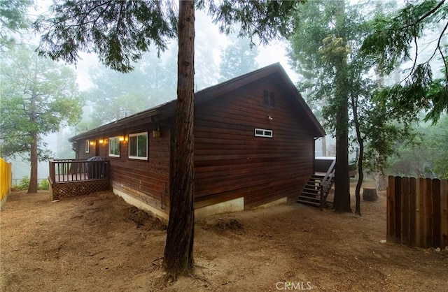 view of property exterior featuring stairway, fence, and a deck