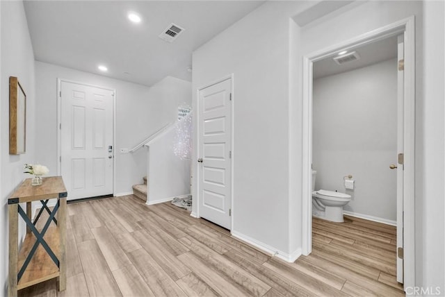 foyer featuring light wood-style flooring, visible vents, baseboards, and stairway