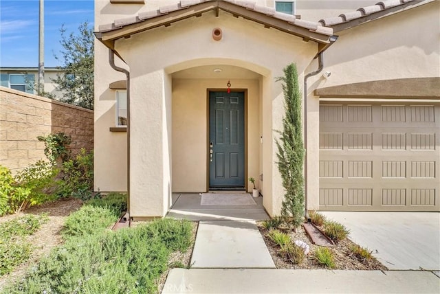 doorway to property with stucco siding, a tile roof, fence, and a garage