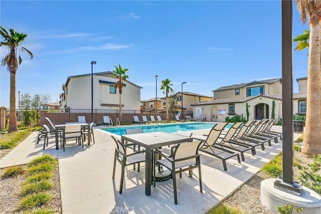 pool with fence, a patio area, and a residential view