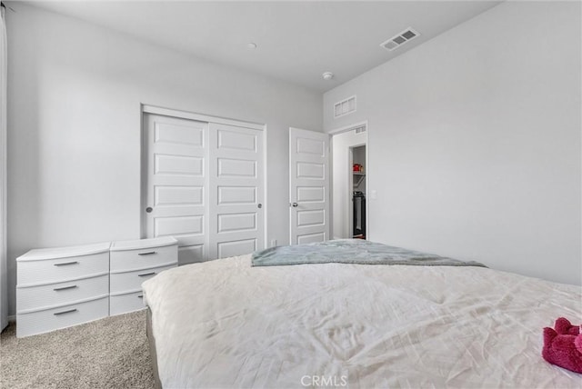carpeted bedroom with visible vents and a closet