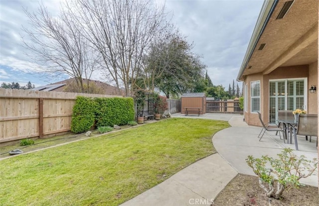 view of yard featuring a patio area, a fenced backyard, an outbuilding, and a shed