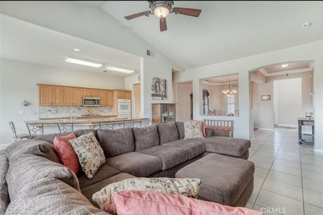 living area featuring visible vents, light tile patterned flooring, arched walkways, high vaulted ceiling, and ceiling fan with notable chandelier