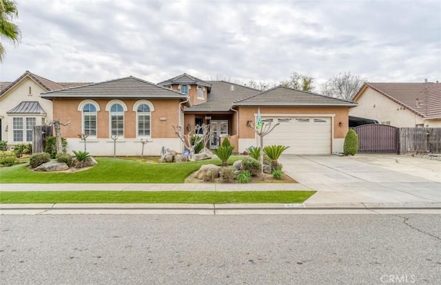 view of front of home with a front lawn, a gate, concrete driveway, an attached garage, and stucco siding