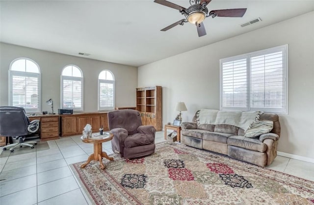 living area featuring plenty of natural light, a ceiling fan, visible vents, and light tile patterned flooring