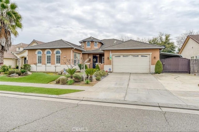 view of front of property with a garage, driveway, a gate, and stucco siding