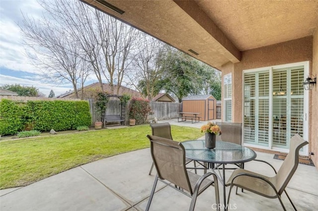 view of patio / terrace with outdoor dining area, an outdoor structure, a fenced backyard, and a storage unit