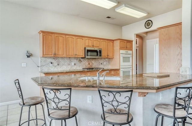 kitchen with backsplash, a kitchen bar, visible vents, and stainless steel appliances