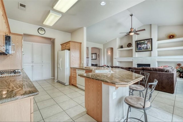 kitchen featuring a peninsula, arched walkways, a kitchen bar, a ceiling fan, and appliances with stainless steel finishes