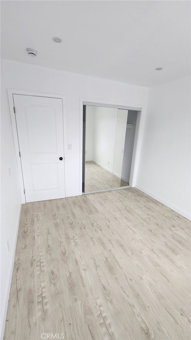 11114 Willowbrook Ave, Los Angeles, CA 90059 - unfurnished bedroom featuring light wood-type flooring, a closet, and baseboards